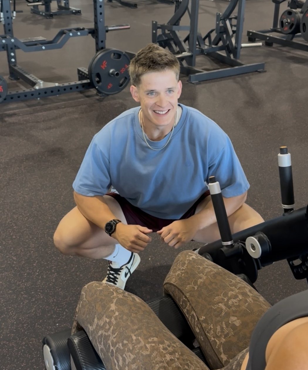 Trey crouched down in the gym, smiling at the camera